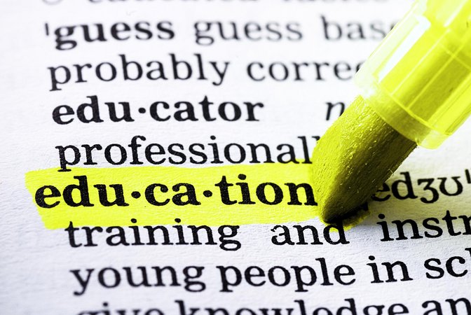 Auf dem Bild ist ein aufgeschlagenes Wörterbuch zu sehen, das Wort "education" wird von einem gelben Marker unterstrichen. 