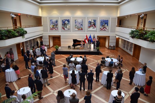 Hall with a stage, bar tables and many guests