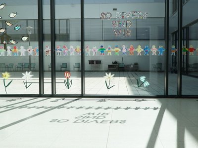 Ein Fenster mit Figuren und Vögelmotiven, durch das Sonnenlicht scheint. 