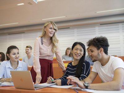 Vier weibliche und männliche Studierende mit Laptop im Hörsaal