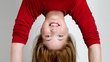 A young woman with dark blonde hair does a headstand.