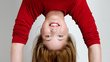 A young woman with dark blonde hair does a headstand.