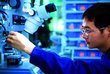 Young student adjusts a microscope.