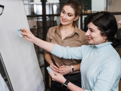 Personen unterhalten sich und kleben Zettel an ein Flipchart
