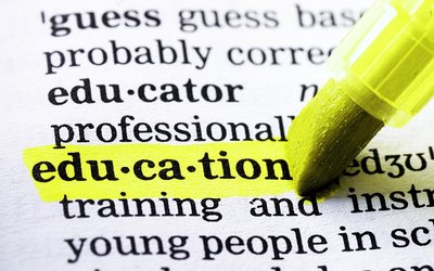 Auf dem Bild ist ein aufgeschlagenes Wörterbuch zu sehen, das Wort "education" wird von einem gelben Marker unterstrichen. 