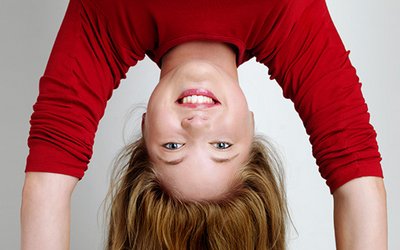 A young woman with dark blonde hair does a headstand.