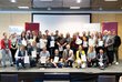 Gruppenbild mit ca. 35 Personen auf einer Bühne, die meisten halten ein Zertifikat in der Hand