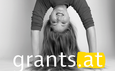 The subject of grants.at shows a young woman with long hair who makes a handstand.