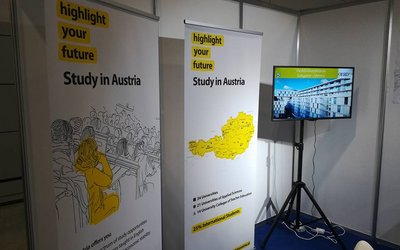 Der Österreichstand bei der Ghedex-Messe im Oman: Im Bild zwei Plakate mit Österreich-Motiven und ein großer Bildschirm.