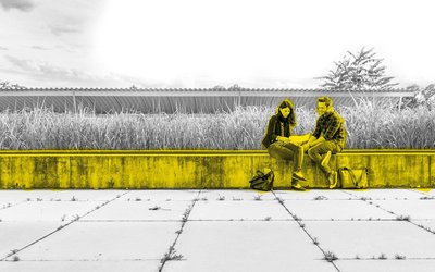 Zwei Studierende sitzen auf einer Steinnaumer am Campus.