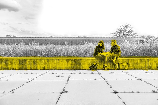 Zwei Studierende sitzen auf einer Steinnaumer am Campus.